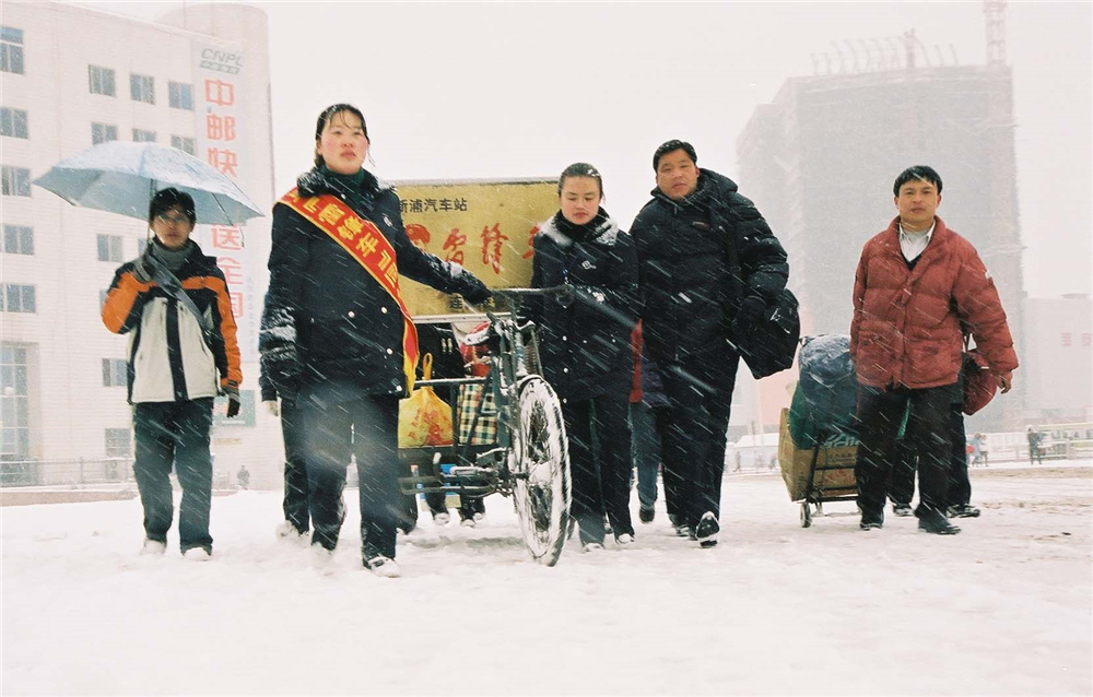 2.2005年2月，雷锋车组张海萍、苏小敏冒着风雪帮旅客拉运行李.jpg